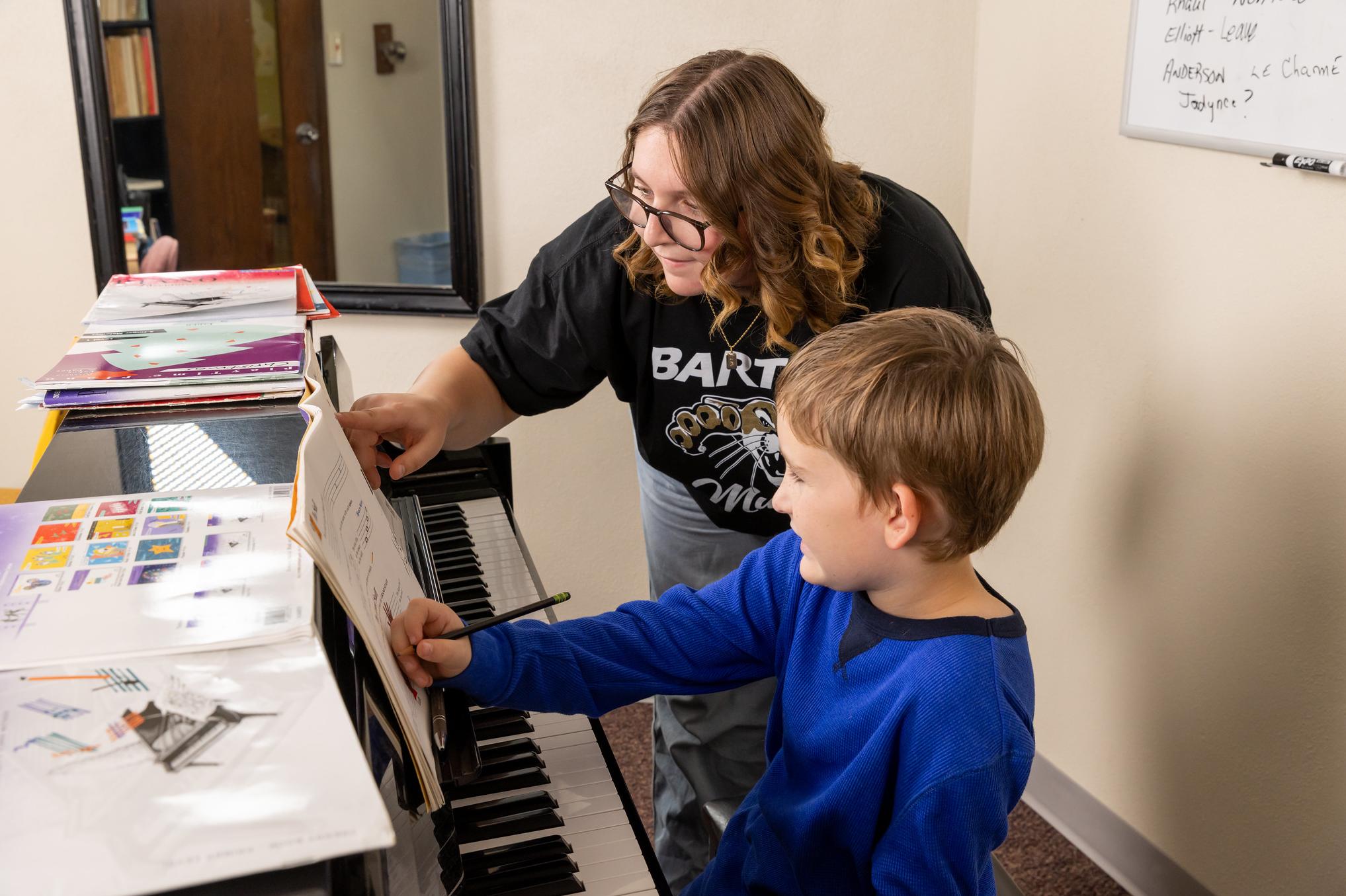 a college student working with a young child on piano lessons